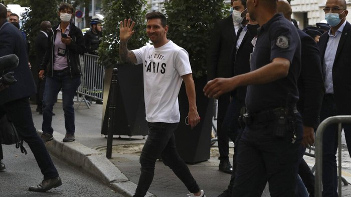 Argentinian soccer star Lionel Messi waves to supporters as he arrives at his hotel in Paris, Tuesday, Aug. 10, 2021. Lionel Messi finalized agreement on his Paris Saint-Germain contract and arrived in the French capital on Tuesday to complete the move that confirms the end of a career-long association with Barcelona. (AP Photo/Adrienne Surprenant)