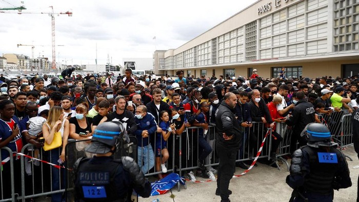 Potret Messi Memulai Petualangan Baru di PSG Supporters stand behind a fence upon Argentinian football player Lionel Messi (not seen) arrival on August 10, 2021 at Le Bourget airport, north of Paris, as Paris Saint-Germain look to complete the 34-year-old signing following his departure from Barcelona. - Asked by reporters at Barcelona's El Prat airport if the Argentine star would later on sign with the French club, Jorge Messi, the father and player's agent, said: