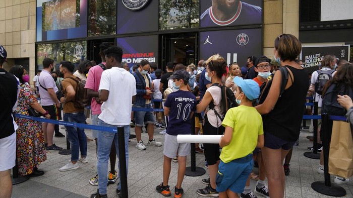 A Parsi Saint-Germain supporter shows a jersey bearing the name of Lionel Messi he just bought as Scarlett Su, right, from New York, smiles outside the official PSG shop, Wednesday, Aug. 11, 2021 in Paris. Lionel Messi is a 