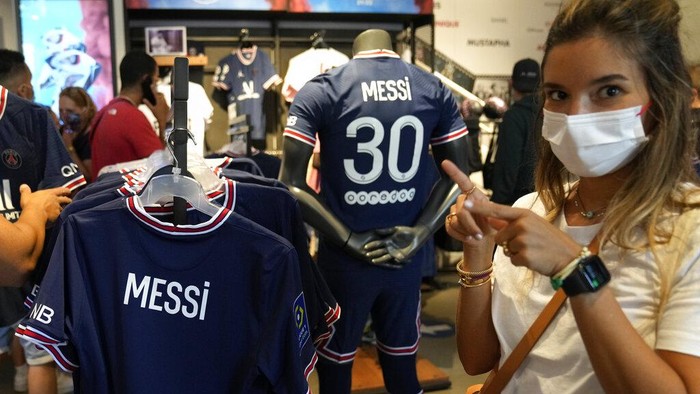 A Parsi Saint-Germain supporter gestures by jerseys bearing the name of Lionel Messi in the official PSG shop, Wednesday, Aug. 11, 2021 in Paris. Lionel Messi said hes 