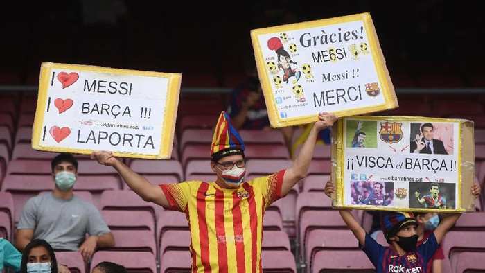 BARCELONA, SPAIN - AUGUST 15: Fans of FC Barcelona hold aloft signs in support of the club and former player Lionel Messi prior to the LaLiga Santander match between FC Barcelona and Real Sociedad at Camp Nou on August 15, 2021 in Barcelona, Spain. FC Barcelona will host between 20,000 and 22,0000 fans in the stadium as the Regional government has authorised a capacity of 30 percent with the requirement to maintain a meter and a half distance between people or groups of people who have tickets. (Photo by Alex Caparros/Getty Images)