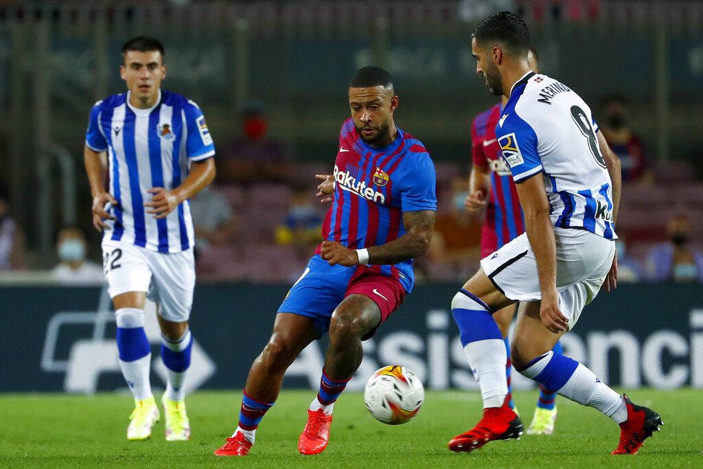 Real Sociedad's Mikel Merino, right, vies for the ball with Barcelona's Memphis Depay during a Spanish La Liga soccer match between Barcelona and Real Sociedad at Camp Nou stadium in Barcelona, Spain, Sunday, Aug. 15, 2021. (AP Photo/Joan Monfort)