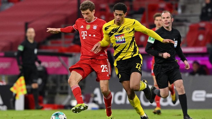 MUNICH, GERMANY - MARCH 06: Thomas Mueller of FC Bayern Muenchen and Jude Bellingham of Borussia Dortmund  battle for the ball  during the Bundesliga match between FC Bayern Muenchen and Borussia Dortmund at Allianz Arena on March 06, 2021 in Munich, Germany. Sporting stadiums around Germany remain under strict restrictions due to the Coronavirus Pandemic as Government social distancing laws prohibit fans inside venues resulting in games being played behind closed doors. (Photo by Sebastian Widmann/Getty Images)