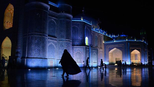 An Afghan woman walks in the courtyard of Hazrat-e Ali shrine, or 'Blue Mosque' in the northern city of Mazar-e Sharif on April 17, 2014. The mosque, whose origins date back to the 12th century BC, includes gardens with places for residents to sit or walk around.  AFP PHOTO/FARSHAD USYAN (Photo by FARSHAD USYAN / AFP)