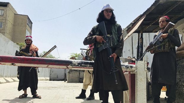 Taliban fighters patrol as two Traffic policemen stand, left, in Kabul, Afghanistan, Thursday, Aug. 19, 2021. The Taliban celebrated Afghanistan's Independence Day on Thursday by declaring they beat the United States, but challenges to their rule ranging from running a country severely short on cash and bureaucrats to potentially facing an armed opposition began to emerge. (AP Photo/Rahmat Gul)