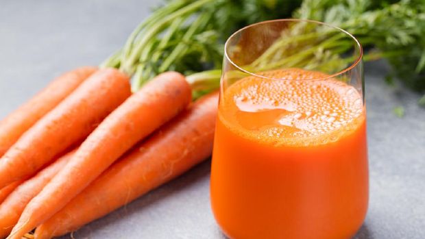 Carrot juice in glass and fresh carrots Healthy food on a grey stone background.