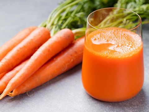 Carrot juice in glass and fresh carrots Healthy food on a grey stone background.