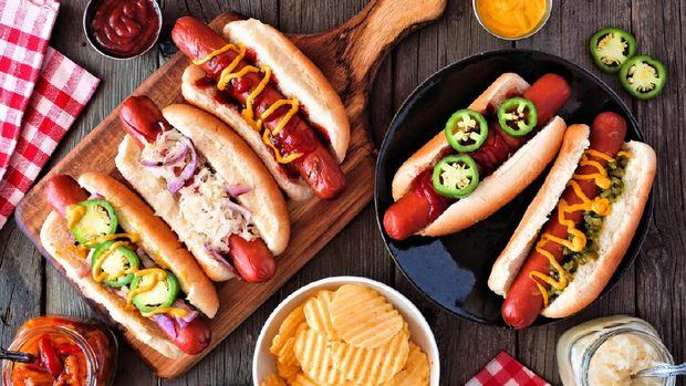 BBQ hot dog table scene. Top view over a dark wood background.