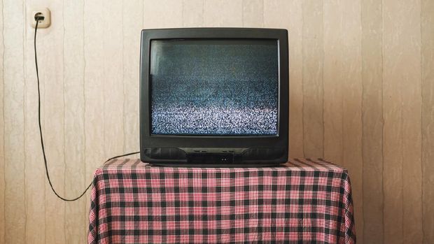 Old TV with small screen broadcasting flickering black and white image with noise