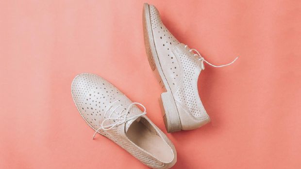 beige oxford shoes on pink background. Top view