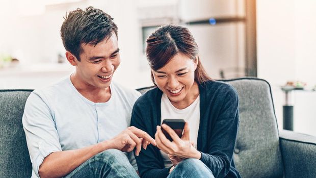 Asian ethnicity couple with smart phone at home