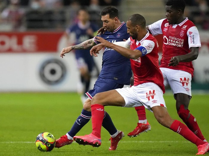 Reims' Marshall Munetsi, left, challenges for the ball with PSG's Lionel Messi during the France League One soccer match between Reims and Paris Saint-Germain, at the Stade Auguste-Delaune in Reims, France, Sunday, Aug. 29, 2021. (AP Photo/Francois Mori)