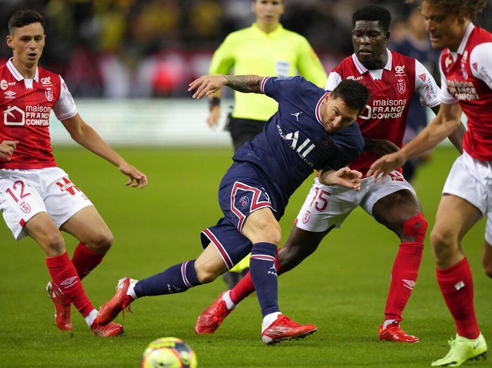 Reims' Marshall Munetsi, left, challenges for the ball with PSG's Lionel Messi during the France League One soccer match between Reims and Paris Saint-Germain, at the Stade Auguste-Delaune in Reims, France, Sunday, Aug. 29, 2021. (AP Photo/Francois Mori)