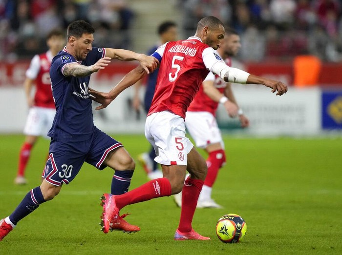 Reims' Marshall Munetsi, left, challenges for the ball with PSG's Lionel Messi during the France League One soccer match between Reims and Paris Saint-Germain, at the Stade Auguste-Delaune in Reims, France, Sunday, Aug. 29, 2021. (AP Photo/Francois Mori)