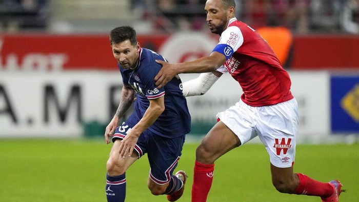 Aksi Lionel Messi Saat Debut Bareng PSG Reims' Marshall Munetsi, left, challenges for the ball with PSG's Lionel Messi during the France League One soccer match between Reims and Paris Saint-Germain, at the Stade Auguste-Delaune in Reims, France, Sunday, Aug. 29, 2021. (AP Photo/Francois Mori)