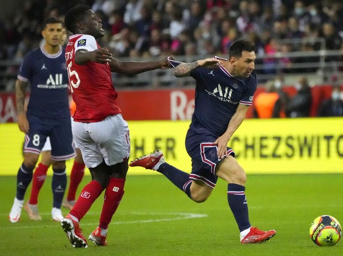 Reims' Marshall Munetsi, left, challenges for the ball with PSG's Lionel Messi during the France League One soccer match between Reims and Paris Saint-Germain, at the Stade Auguste-Delaune in Reims, France, Sunday, Aug. 29, 2021. (AP Photo/Francois Mori)