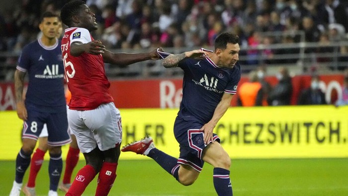 Reims Marshall Munetsi, left, challenges for the ball with PSGs Lionel Messi during the France League One soccer match between Reims and Paris Saint-Germain, at the Stade Auguste-Delaune in Reims, France, Sunday, Aug. 29, 2021. (AP Photo/Francois Mori)