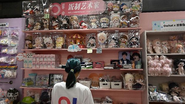 A salesperson checks dolls and celebrity idol-related products at a fan merchandise store at a shopping mall in Beijing on September 2, 2021. (Photo by JADE GAO / AFP)