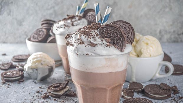 Coffee mocha milkshake with cookies and cream. Ice cream and chocolate cookies sweet latte cocktail. On gray concrete table, with spoon and cup of vanilla ice cream. Copy space