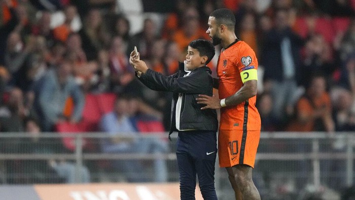 A young fan ran onto the pitch to take a selfie with Memphis Depay of the Netherlands during the World Cup 2022 group G qualifying soccer match between the Netherlands and Montenegro at the Philips stadium in Eindhoven, Netherlands, Saturday, Sept. 4, 2021. (AP Photo/Peter Dejong)