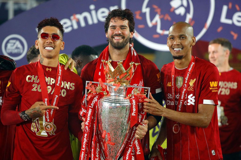 LIVERPOOL, ENGLAND - JULY 22: Roberto Firmino, Alisson Becker and Fabinho of Liverpool celebrate with The Premier League trophy following the Premier League match between Liverpool FC and Chelsea FC at Anfield on July 22, 2020 in Liverpool, England. Football Stadiums around Europe remain empty due to the Coronavirus Pandemic as Government social distancing laws prohibit fans inside venues resulting in all fixtures being played behind closed doors. (Photo by Phil Noble/Pool via Getty Images)