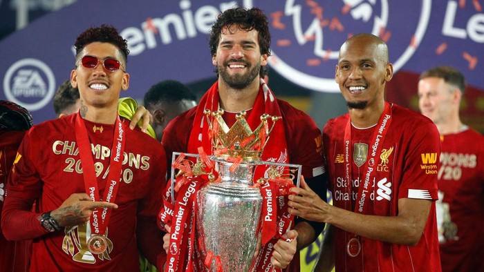 LIVERPOOL, ENGLAND - JULY 22: Roberto Firmino, Alisson Becker and Fabinho of Liverpool celebrate with The Premier League trophy following the Premier League match between Liverpool FC and Chelsea FC at Anfield on July 22, 2020 in Liverpool, England. Football Stadiums around Europe remain empty due to the Coronavirus Pandemic as Government social distancing laws prohibit fans inside venues resulting in all fixtures being played behind closed doors. (Photo by Phil Noble/Pool via Getty Images)