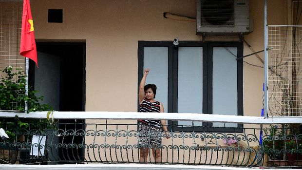 This picture taken on September 5, 2021 shows a woman exercising on the balcony of her home in Hanoi, during the government-imposed lockdown to stop the spread of the Covid-19 coronavirus. - Overlooking deserted streets, Hanoi's tiny balconies have become places of refuge as the city's locked-down residents squeeze desks, yoga mats and comfy seats for coffee into their bit of fresh air. (Photo by Nhac NGUYEN / AFP) / TO GO WITH Vietnam-health-virus, PHOTOESSAY by Nhac Nguyen