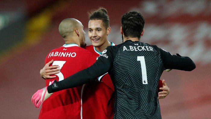 LIVERPOOL, ENGLAND - DECEMBER 16: Rhys Williams of Liverpool celebrates with teammates Fabinho and Alisson Becker at full-time after the Premier League match between Liverpool and Tottenham Hotspur at Anfield on December 16, 2020 in Liverpool, England. A limited number of fans (2000) are welcomed back to stadiums to watch elite football across England. This was following easing of restrictions on spectators in tiers one and two areas only. (Photo by Clive Brunskill/Getty Images)