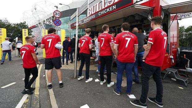 Fans wearing Manchester United's Cristiano Ronaldo shirts queue at a food stand outside the stadium before the English Premier League soccer match between Manchester United and Newcastle United at Old Trafford stadium in Manchester, England, Saturday, Sept. 11, 2021. (AP Photo/Jon Super)