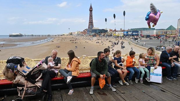 wisata tepi laut inggris People relax on benches set out on the Central Pier in Blackpool, north west England on September 4, 2021. - Blackpool's Illuminations lights festival crowns an extended tourist season as Britain's traditional seaside resorts benefit from a domestic tourism boom during the coronavirus pandemic. The UK government's ever-changing traffic-light system for international travel has made overseas trips less attractive and even inaccessible for British holidaymakers. (Photo by PAUL ELLIS / AFP) / To go with AFP story by Imran MARASHLI