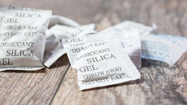 A closeup view of several packets of desiccant silica gel, on a wooden surface.