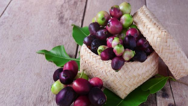 Jambolan plum or Java plum with stem and leaf in bamboo box on wooden background.