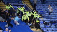 Polisi memukuli suporter dengan pentungan agar kerusuhan segera berakhir. (Foto: Laurence Griffiths/Getty Images)