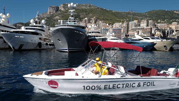 An electric speed boat motors past yachts moored at the Hercules Port in Monaco on September 22, 2021, during the 30th edition of the International Monaco Yacht Show. - The Monaco Yacht Show is considered the most prestigious pleasure boat show in the world with the exhibition of 500 major companies in luxury yachting and featuring over a hundred super and megayachts. (Photo by Valery HACHE / AFP)