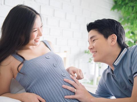 Happy pregnant woman with her husband in the room.