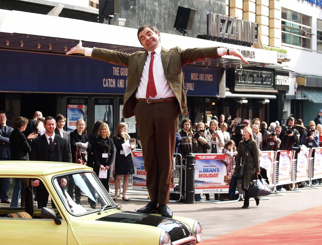 British actor Rowan Atkinson stands on the bonnet of the car used in the film as he arrives for the British Charity Premiere of his latest film 'Mr. Bean's Holiday' in London's Leicester Square, 25 March 2007.     AFP Photo / Max Nash (Photo by MAX NASH / AFP)