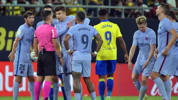 Barcelona's Spanish defender Gerard Pique (3L) remonstrate with the referee after presenting a red card to Barcelona's Dutch midfielder Frenkie De Jong (2R) during the Spanish League football match between Cadiz CF and FC Barcelona at the Ramon de Carranza stadium in Cadiz on September 23, 2021. (Photo by CRISTINA QUICLER / AFP)
