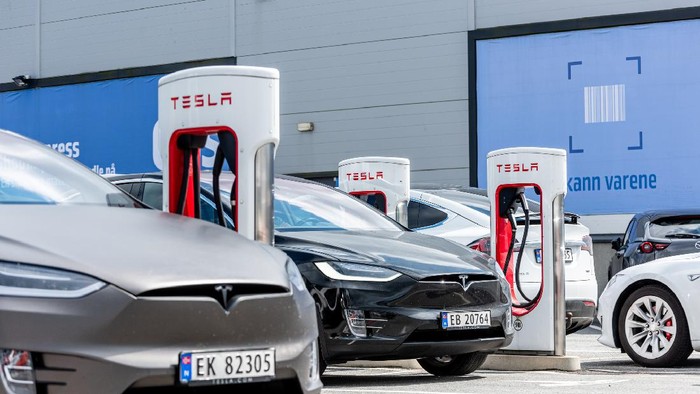 Pengisian baterai kendaraan beroda empat listrik Tesla Lyngdal, Norway - August 02 2021: Tesla Superchargers at use at Handelsparken.