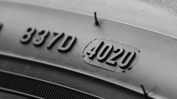Dot code and date of production of the tire on the sidewall of the wheel close-up, tire shelf .