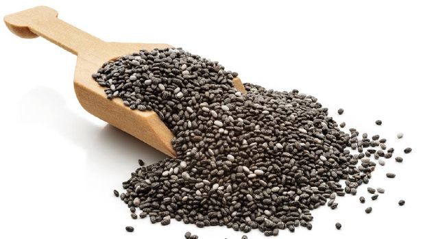 Chia seeds in a wooden serving scoop. Isolated on a white background.