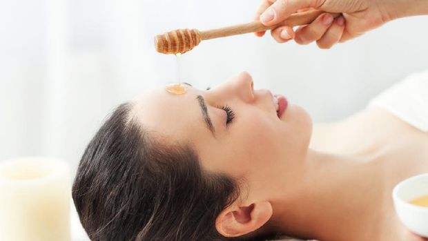 Woman having honey facial massage at spa salon