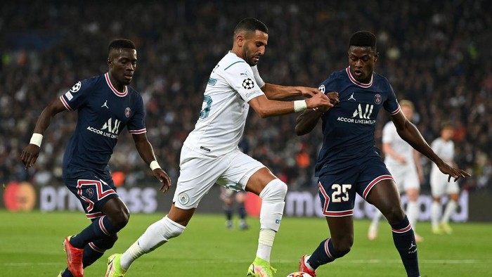 Manchester City PARIS, FRANCE - SEPTEMBER 28: Riyad Mahrez of Manchester City runs with the ball whilst under pressure from Nuno Mendes of Paris Saint-Germain during the UEFA Champions League group A match between Paris Saint-Germain and Manchester City at Parc des Princes on September 28, 2021 in Paris, France. (Photo by Shaun Botterill/Getty Images)
