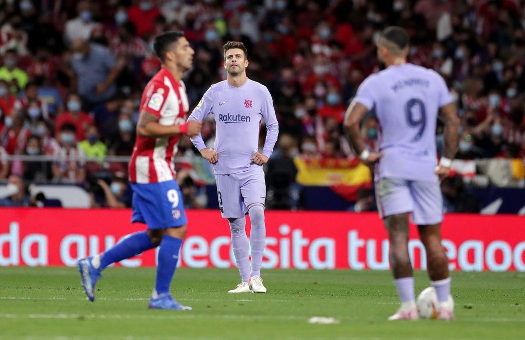 MADRID, SPAIN - OCTOBER 02: Gerard Pique of FC Barcelona  looks dejected as Luis Suarez of Atletico Madrid celebrates after scoring their team's second goal during the La Liga Santander match between Club Atletico de Madrid and FC Barcelona at Estadio Wanda Metropolitano on October 02, 2021 in Madrid, Spain. (Photo by Gonzalo Arroyo Moreno/Getty Images)
