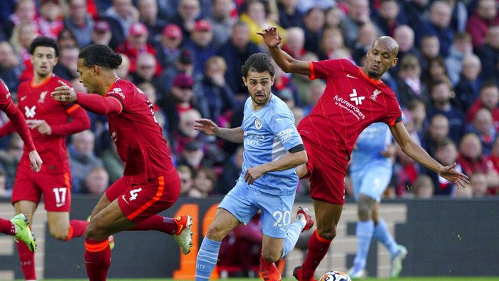 Manchester Citys Bernardo Silva, center, battles with Liverpools Virgil van Dijk, left, and Fabinho during the English Premier League soccer match between Liverpool and Manchester City at Anfield, Liverpool, England, Sunday Oct. 3, 2021. (Peter Byrne/PA via AP)