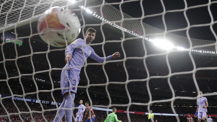 Barcelonas Gerard Pique looks round as Atletico Madrids Luis Suarez, center rear, celebrates after scoring his sides second goal during the La Liga soccer match between Atletico Madrid and Barcelona at the Estadio Wanda Metropolitano in Madrid, Saturday, Oct. 2, 2021. (AP Photo/Manu Fernandez)
