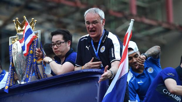 Leicester City's Italian manager Claudio Ranieri (C) gestures as he along with the club's football players and owners parade in an open-bus with the Premier League trophy through Bangkok on May 19, 2016. - Newly crowned English Premier League champions Leicester City received a royal seal of approval on May 19 at Bangkok's Grand Palace, with the Thai-owned team presenting its trophy to a portrait of the king before a bus parade through the capital. (Photo by CHRISTOPHE ARCHAMBAULT / AFP)