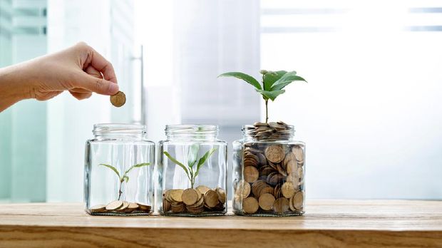 Woman putting coin in the jar with plant.