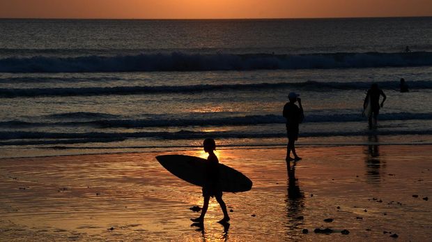People enjoy the sunset at Kuta beach near Denpasar on Indonesia resort island of Bali on September 6, 2021. (Photo by SONNY TUMBELAKA / AFP)
