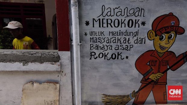 Warga melintasi mural dilarang merokok di RW 06 Kayu Manis. Jakarta, Kamis, 7 Oktober 2021. (CNN Indonesia/Adhi Wicaksono)