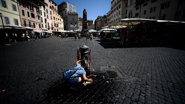 A tourist refreshes herself at a nasone fountain in Piazza Campo de Fiori in central Rome on August 11, 2019. - According to the weather forecast, hot air from North Africa will affect the center and southern Italy with temperatures reaching 40 degrees Celsius.  (Photo by Filippo MONTEFORTE / AFP)